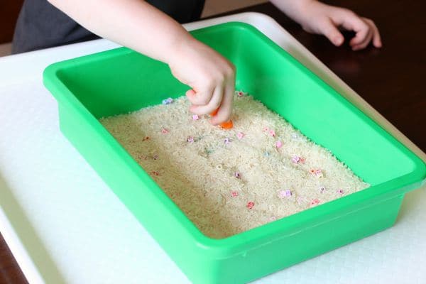 Use squeezy tweezers to pick beads out of rice. Fine motor practice for kids.